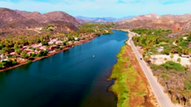 MULEGE BCS MEXICO-2022: Car Driving Along Road Beside River with Mountain Backdrop
