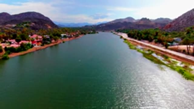 MULEGE BCS MEXICO-2022: River Bordered by Road and Buildings Against Mountains