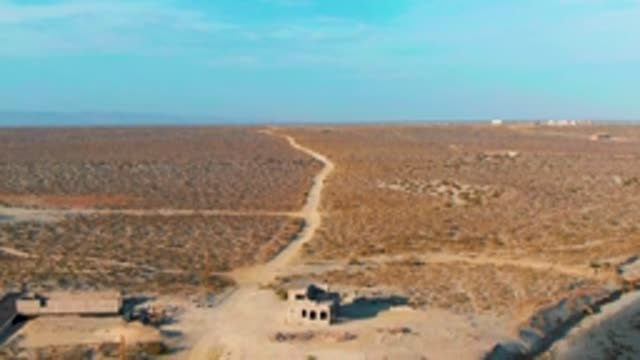 LA BOCANA BCS MEXICO-2022: Desert Road with Abandoned Structures and Sparse Vegetation