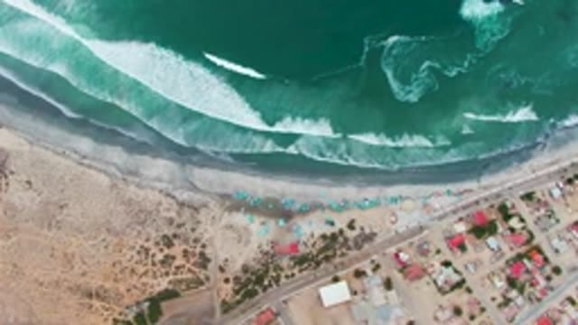 PUENTA ABREOJOS BCS MEXICO-2022: Waves Rolling Onto Sandy Beach with Coastal Buildings