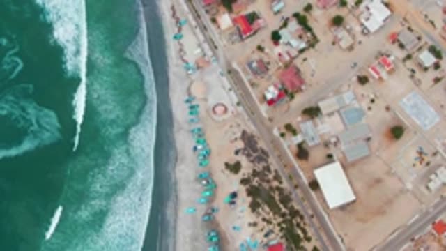 PUENTA ABREOJOS BCS MEXICO-2022: Waves Advancing on Sandy Beach with Blue Umbrellas