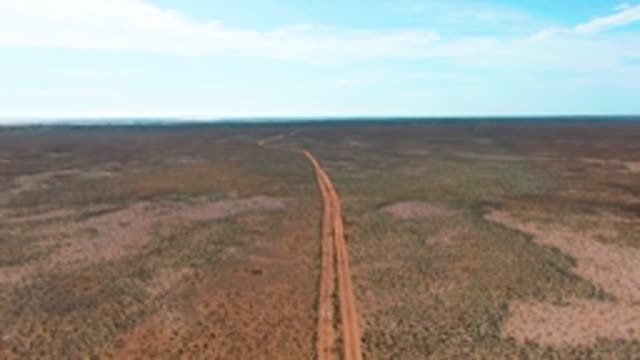 GUERRERO NEGRO BCS MEXICO-2022: Dirt Road in Arid Landscape with Passing Vehicle