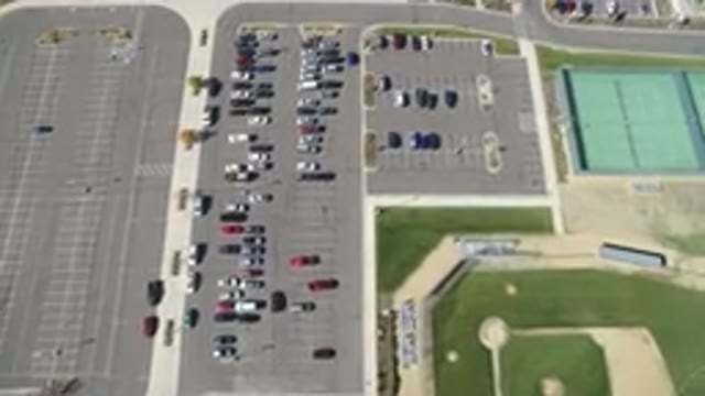 HIDDEN LAKE COLORADO-2016: Cars in Large Parking Space Near Green Field with Person Walking