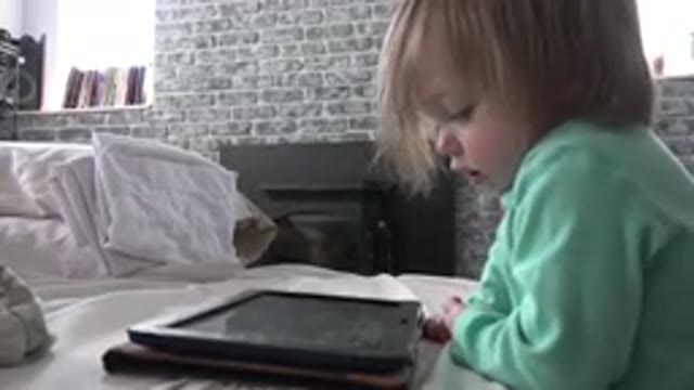 WESTMINSTER COLORADO-2016: Young Child Enjoying Playing On Portable Tablet In Bedroom