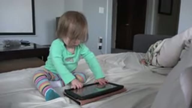 WESTMINSTER COLORADO-2016: Child Wearing Green Shirt Engaging In An Ipad While Sitting On Bed