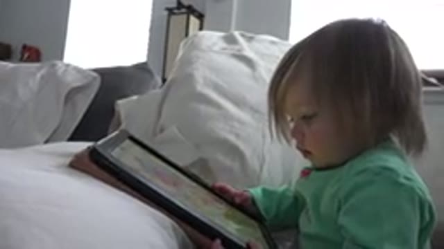 WESTMINSTER COLORADO-2016: Small Child Sitting On A Bed Playing On A Pad
