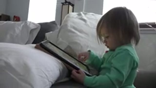 WESTMINSTER COLORADO-2016: Child Blond Hair Wearing Light Green Clothes Hold An iPad on Bed