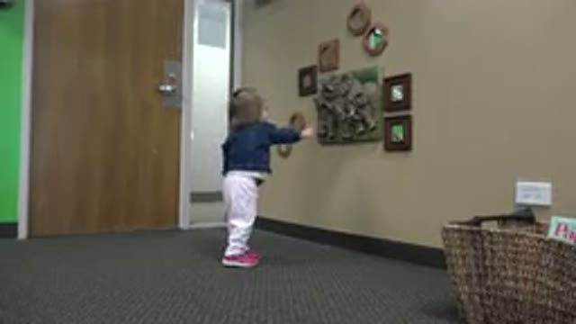 DENVER COLORADO-2016: A Cute Baby Tries To Touch A Frame On The Wall Of A Room