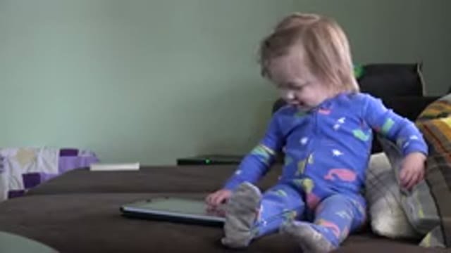 WESTMINSTER COLORADO-2016: Blonde Child Sitting On Bed Plays With Closed Gray Notebook