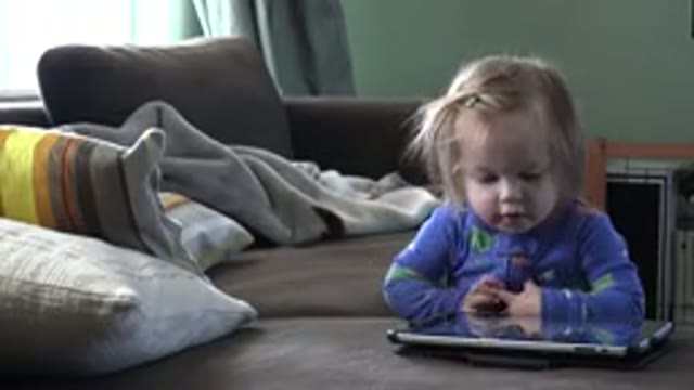 WESTMINSTER COLORADO-2016: Blonde Baby Kid in Pajamas Playing on Tablet in Bedroom