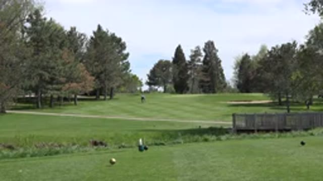 DENVER COLORADO-2015: A Green Grassy Golf Course Intersected By A Creek With A Lone Golfer Walking