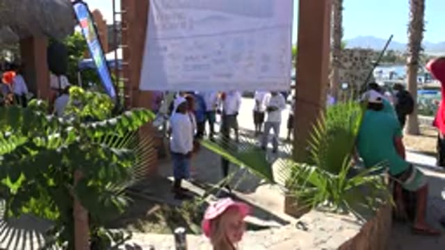 PLAYITA BCS MEXICO-2017: A Large Crowd Stands Outside Under A Big Sign And Talks