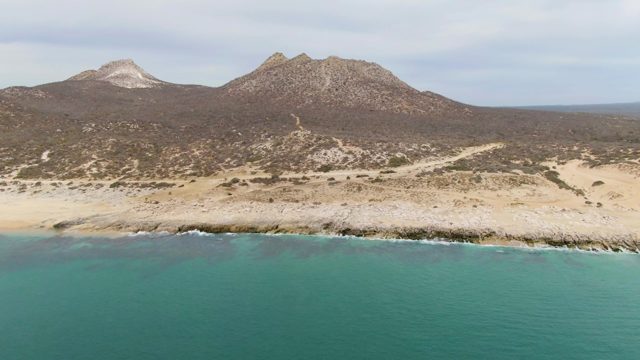 PUNTA GORDA BEACH BCS MEXICO-2023: Coastal Waves Lapping Rocky Shore with Mountain Backdrop