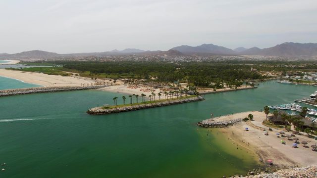 PUERTO LOS CABOS BEACH BCS MEXICO-2023: Coastal Inlet with Breakwater and Moving Boats