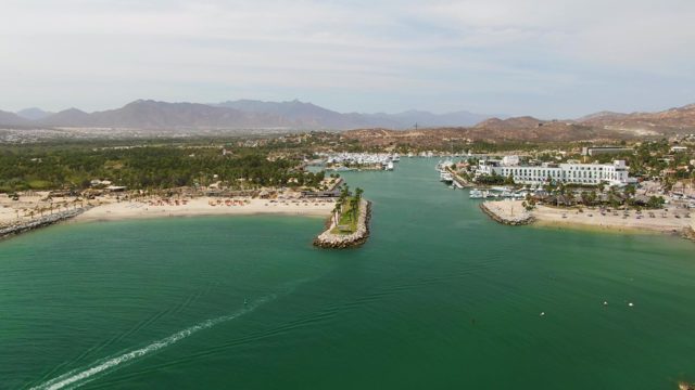 PUERTO LOS CABOS BEACH BCS MEXICO-2023: Boat Moving Through Coastal Water near Beach and Island