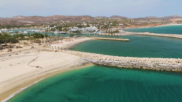 PUERTO LOS CABOS BEACH BCS MEXICO-2023: Sandy Beach, Turquoise Water, and Rocky Breakwater with Gentle Waves