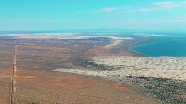 GUERRERO NEGRO BCS MEXICO-2022: Desert Road with Vehicle Traveling Past Salt Flats and Lake