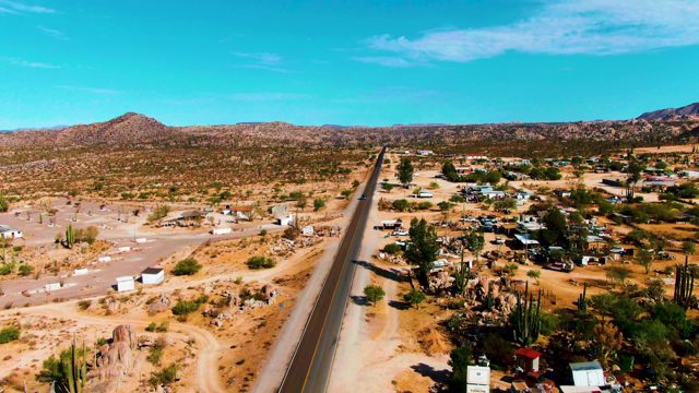 CATAVINA BC MEXICO-2022: Desert Road with Moving Vehicle and Scattered Dwellings