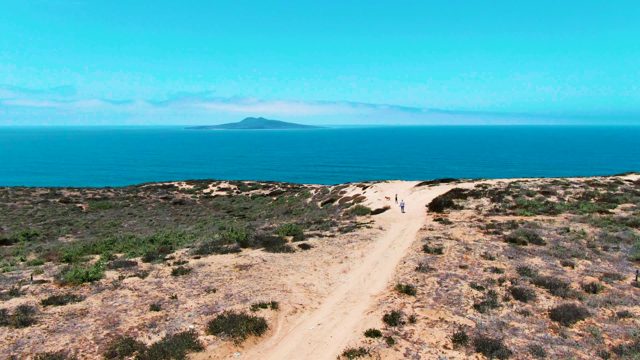 SAN QUINTIN BC MEXICO-2022: Two People Walking on a Coastal Dirt Path