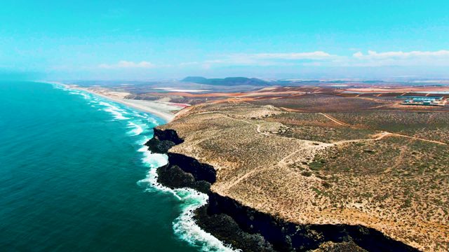 SAN QUINTIN BC MEXICO-2022: Waves Crashing on Rocky Cliffs Along Arid Coast