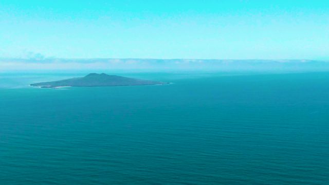 SAN QUINTIN BC MEXICO-2022: Small Island in Calm Ocean with Shifting Clouds