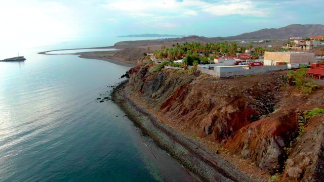 SANTA ROSALIA BCS MEXICO-2022: Cliffside Buildings Overlooking Calm Ocean and Pebbly Shore