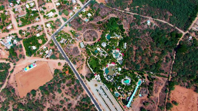 CADUANO BCS MEXICO-2022: Vehicle Moving Across Dirt Field Near Residential Area