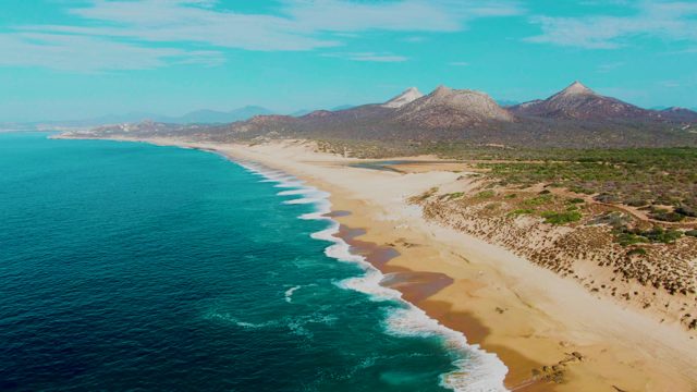 PUNTA BUZZARDS EAST CAPE BCS MEXICO-2022: Waves Rolling Onto Sandy Beach with Distant Mountains