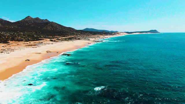 PUNTA BUZZARDS EAST CAPE BCS MEXICO-2022: Waves Rolling Onto Sandy Beach with Mountain Backdrop