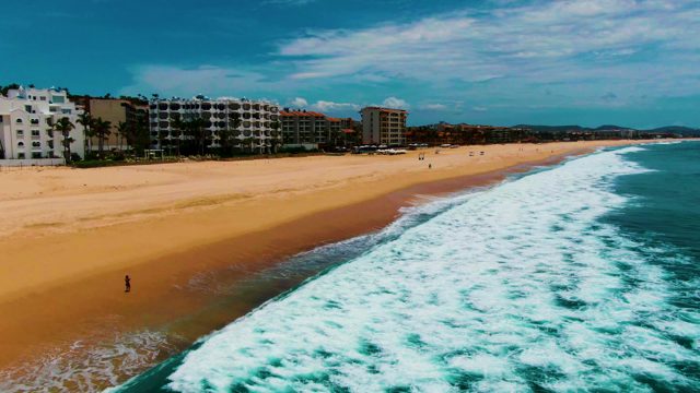 PUNTA BUZZARDS EAST CAPE BCS MEXICO-2022: Waves Rolling Onto Sandy Beach with Coastal Buildings