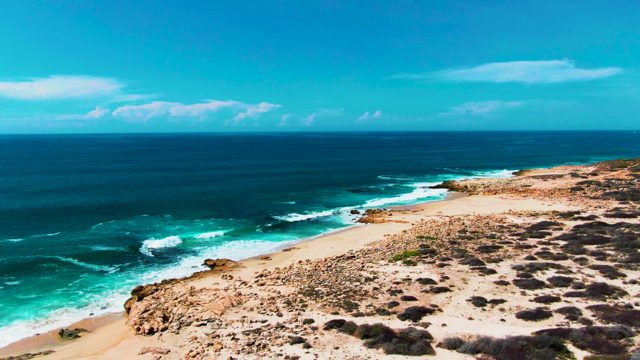 PUNTA BUZZARDS EAST CAPE BCS MEXICO-2022: Waves Crashing on Rocky Shore with Person Walking