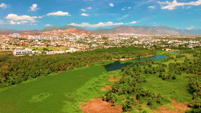 SAN JOSE DEL CABO BCS MEXICO-2022: Aerial Pan of Town, Green Fields, and Mountain Range