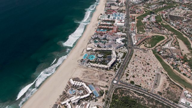 SAN JOSE DEL CABO BCS MEXICO-2022: Ocean Waves Crashing Along Sandy Beach with Coastal Development