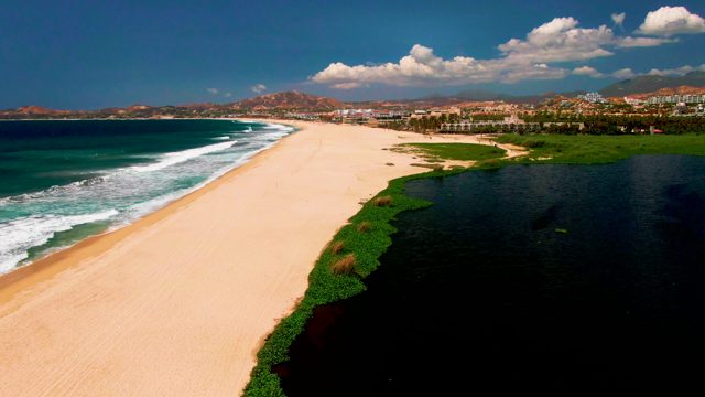 Ocean Waves Rolling Onto Sandy Beach with Lagoon