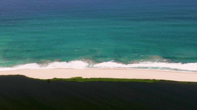 Shifting Shadow over Sandy Beach and Ocean Waves