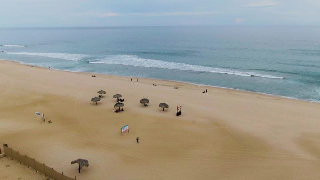 Sandy Beach with Umbrellas and Ocean Waves From Aerial View