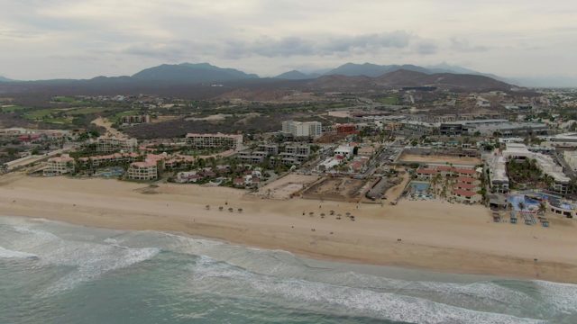 Waves Rolling Along Sandy Beach with Coastal Buildings