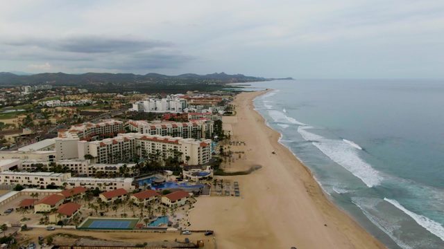 Resort Buildings Along Sandy Beach with Ocean Waves