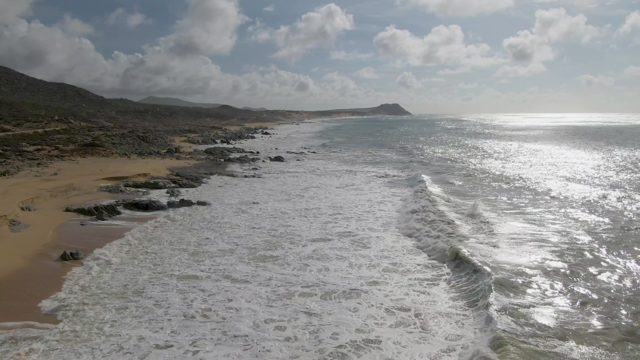 PUNTA GORDO EAST CAPE BCS MEXICO-2022: Waves Crashing Onto Sandy Shore with Rocky Outcrops