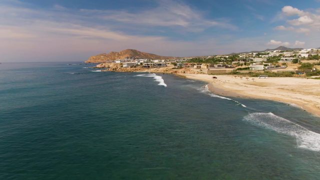 EL TULE LOS CABOS BCS MEXICO-2022: Waves Rolling Along Sandy Shore with Coastal Settlement