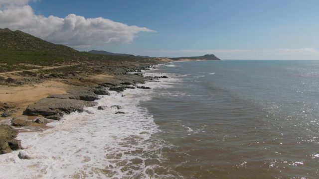 BUZZARDS EAST CAPE LOS CABOS BCS MEXICO-2022: Waves Crashing on Rocky Coastline with Sandy Beach