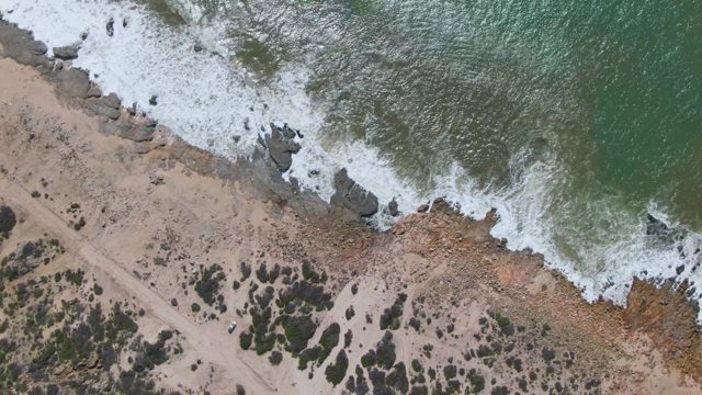 BUZZARDS EAST CAPE LOS CABOS BCS MEXICO-2022: Waves Breaking on Rocky Beach with Moving Vehicle