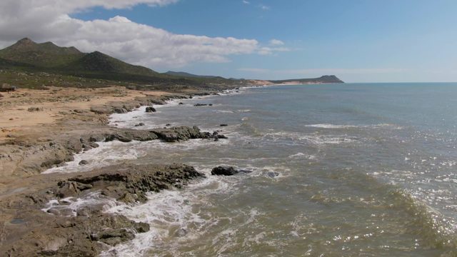 BUZZARDS EAST CAPE LOS CABOS BCS MEXICO-2022: Waves Crashing on Rocky Shore with Distant Mountains
