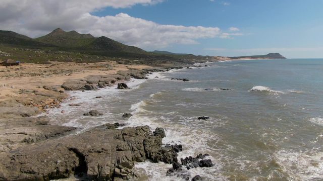 BUZZARDS EAST CAPE LOS CABOS BCS MEXICO-2022: Waves Crashing on Rocky Shoreline with Distant Mountains