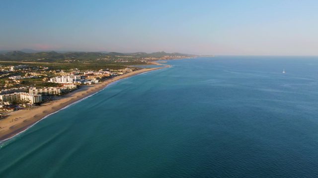 SAN JOSE DEL CABO BCS MEXICO-2022: Beachgoer Walking on Sandy Shore by Coastal Buildings