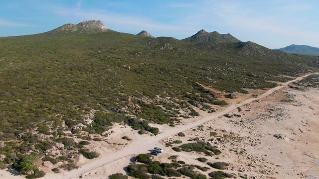 BUZZARDS EAST CAPE LOS CABOS BCS MEXICO-2022: Car Moving Along a Dusty Mountain Road