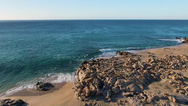BUZZARDS EAST CAPE LOS CABOS BCS MEXICO-2022: Waves Gently Lapping Against Rocky Beach Shore