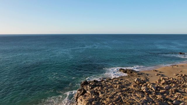 BUZZARDS EAST CAPE LOS CABOS BCS MEXICO-2022: Waves Crashing Against Rocky Shore Overlooking Beach