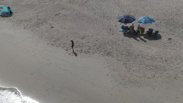 PLAYA EL ARBOLITO CABO PULMO BCS MEXICO-2022: Adult and Child Walking on Sandy Beach near Umbrellas