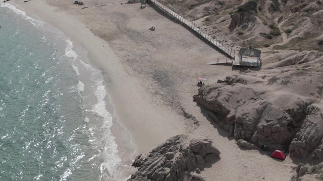 PLAYA EL ARBOLITO CABO PULMO BCS MEXICO-2022: People Moving Along a Sandy and Rocky Beach Shore